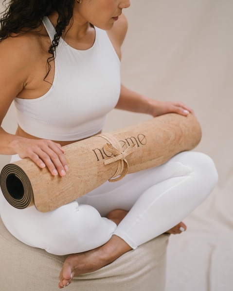 A close-up, serene shot of a practitioner holding a rolled-up cork yoga mat, highlighting the natural texture and clean branding.